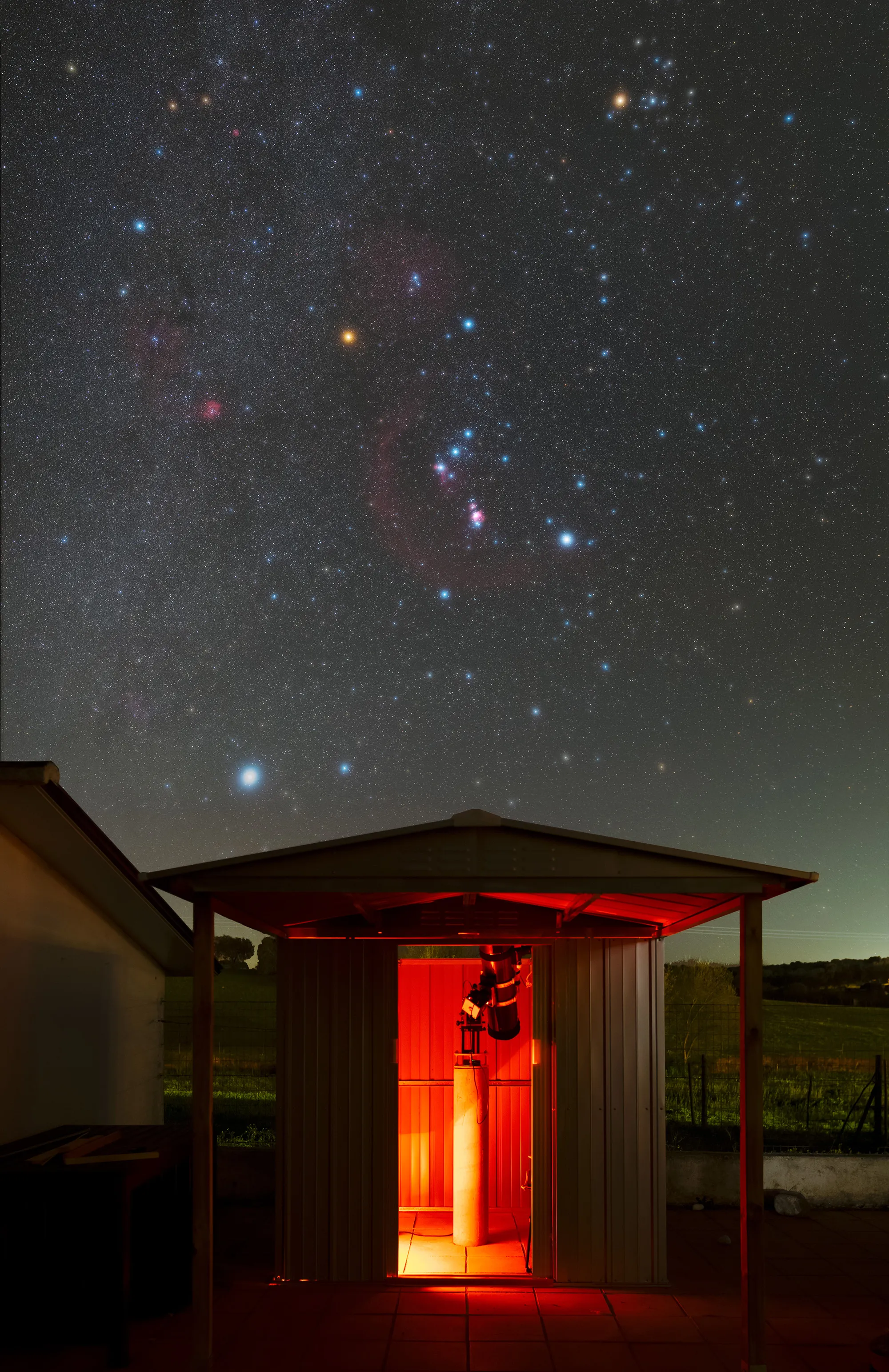 O observatório iluminado a vermelho, com a constelação de Orionte no céu