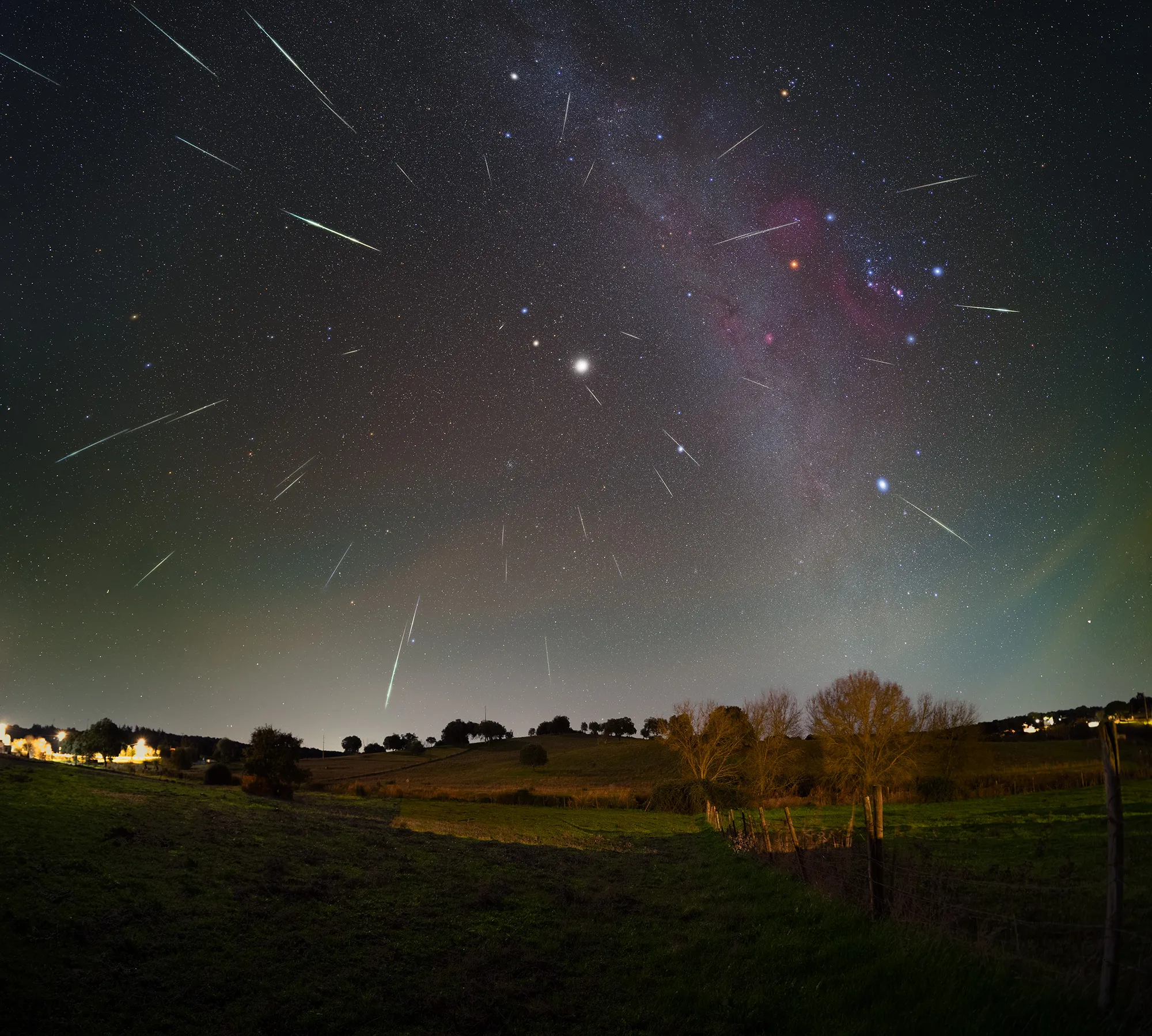 Dezenas de meteoros das Gemínidas a irradiar de um ponto do céu, sobre a paisagem alentejana