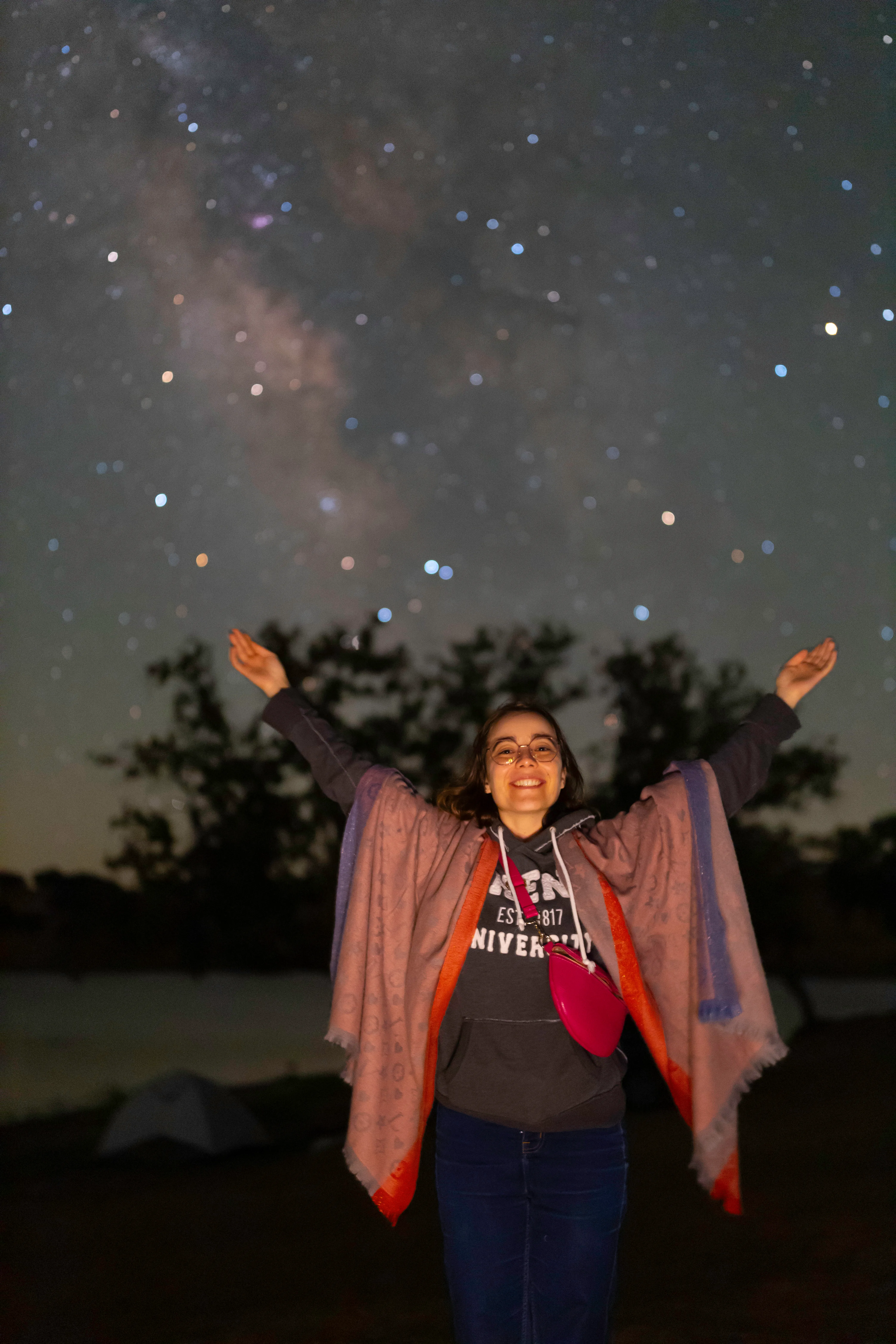 Retrato sob as estrelas com os braços erguidos para o céu